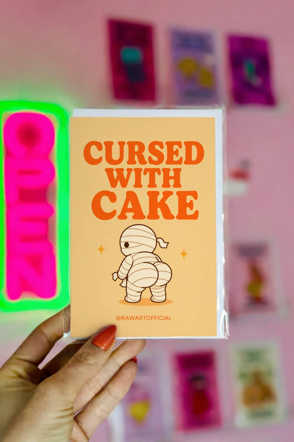 Funny Halloween greeting card with mummy showing a cheeky booty on cream background saying “Cursed With Cake”