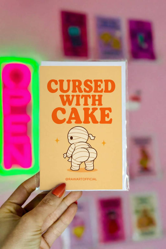 Funny Halloween greeting card with mummy showing a cheeky booty on cream background saying “Cursed With Cake”