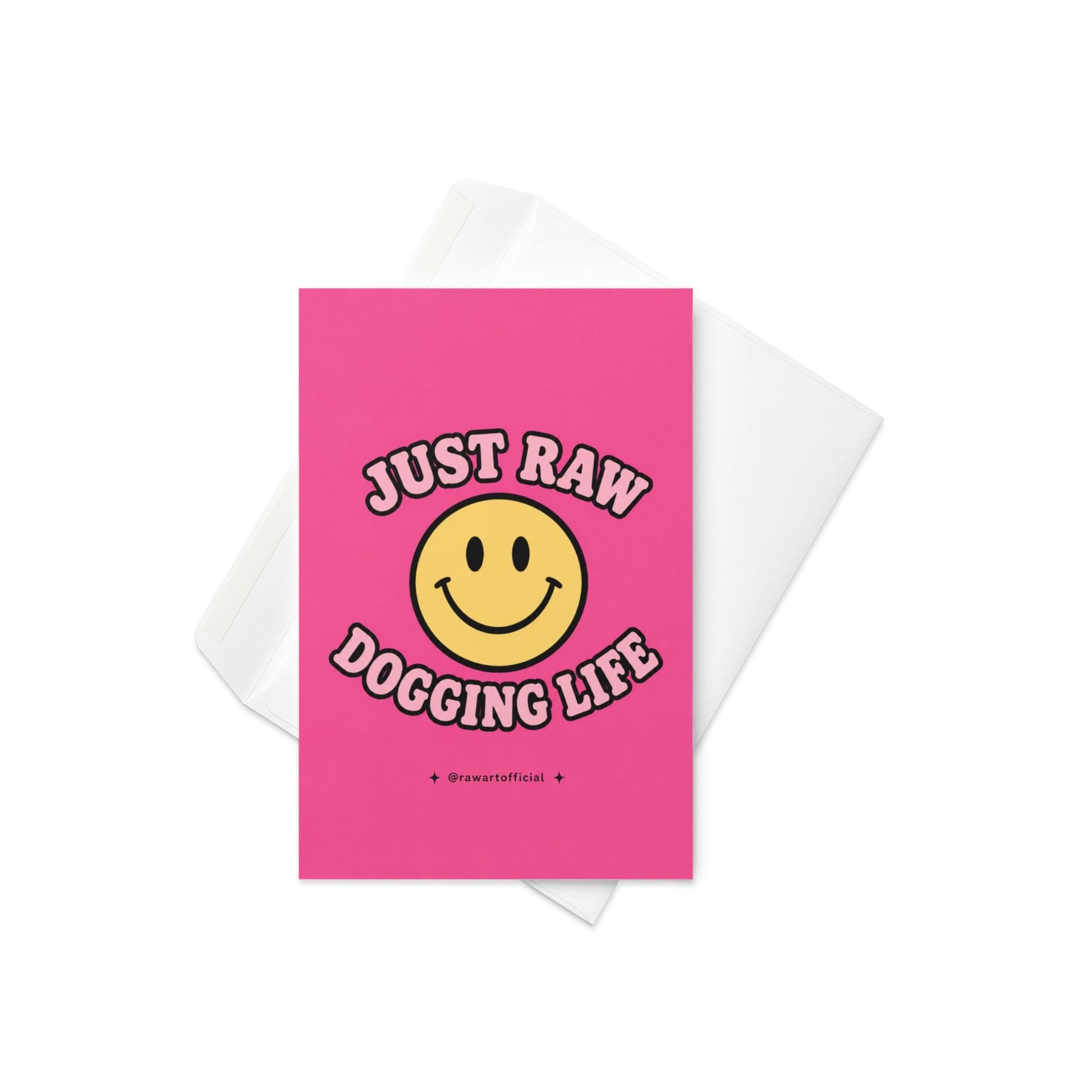Funny pink greeting card with a retro smiley face and the text “Just Raw Dogging Life” in bubble lettering.