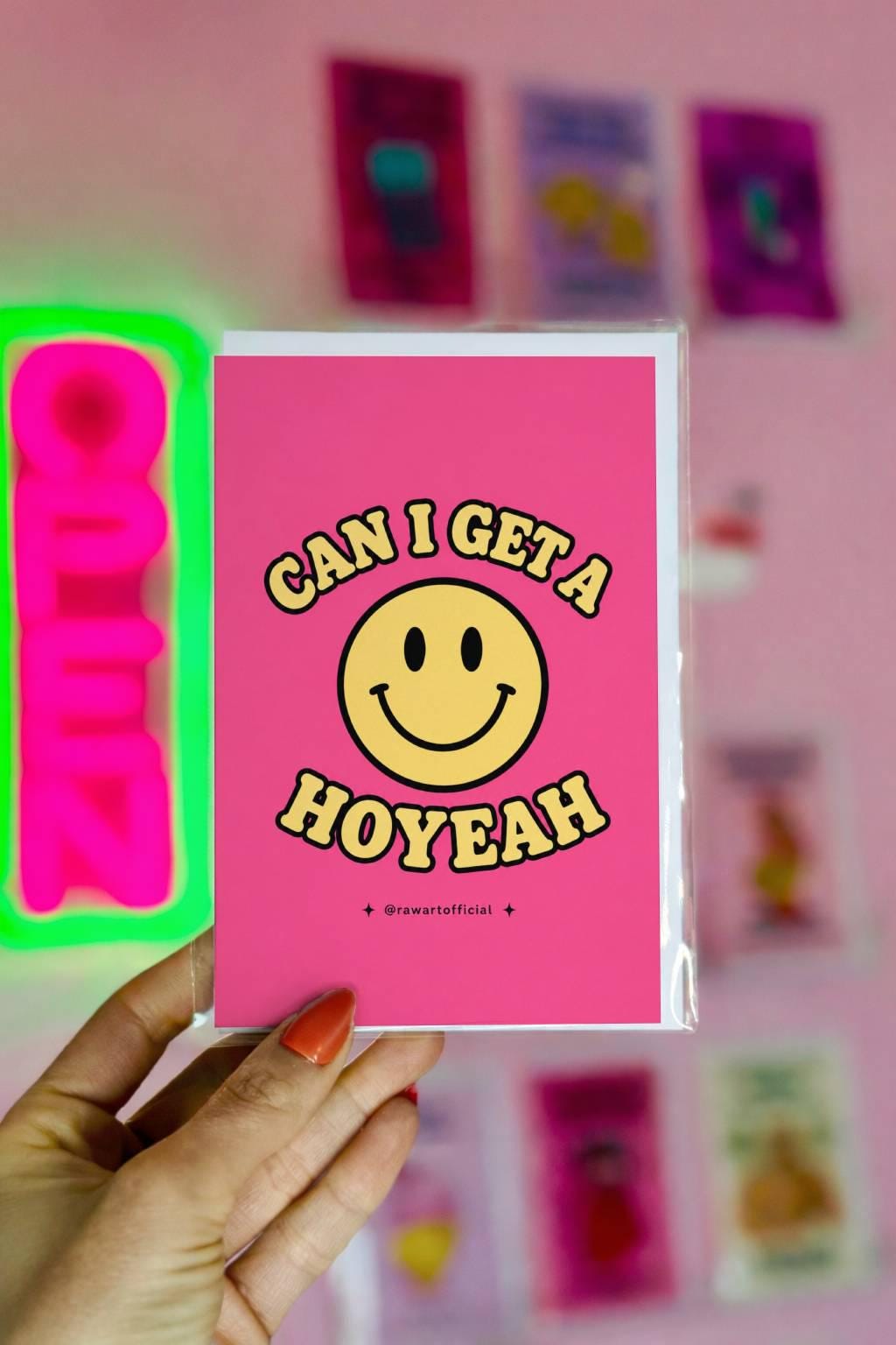 Funny pink greeting card with a retro smiley face and the phrase “Can I Get a Hoyeah” in retro bubble lettering.