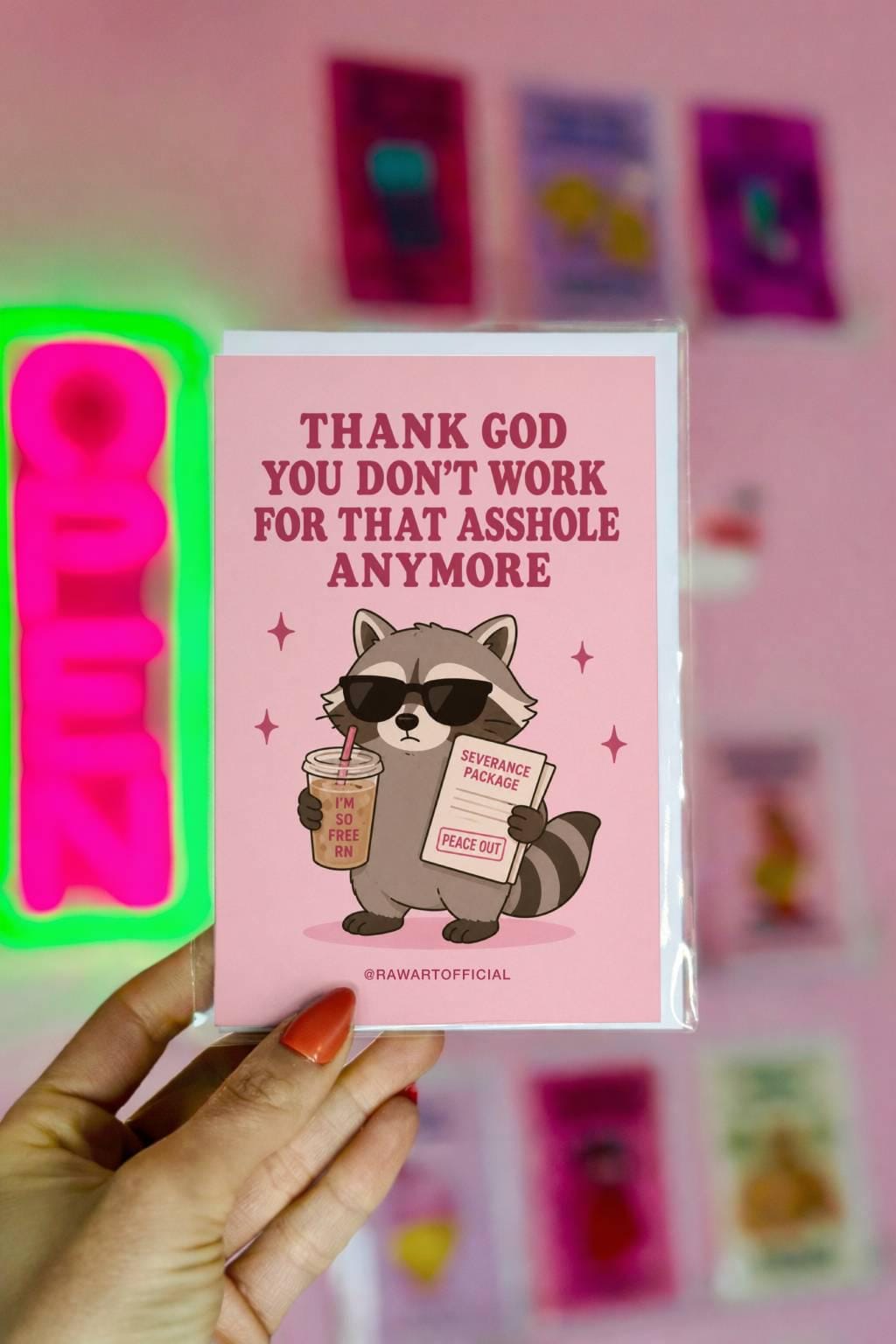 Funny quitting job card with a raccoon in sunglasses holding coffee and severance papers beside the phrase “Thank God You Don’t Work For That Asshole Anymore.”
