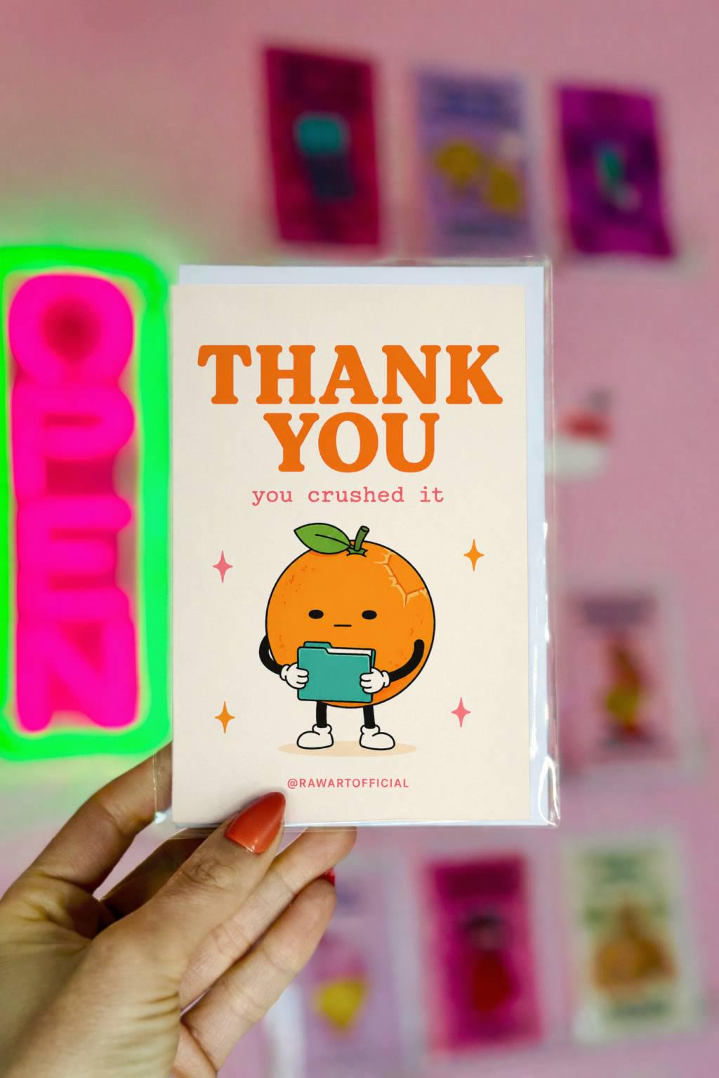Funny coworker thank you greeting card with cartoon orange holding clipboard saying “Thank You, you crushed it” on cream background.
