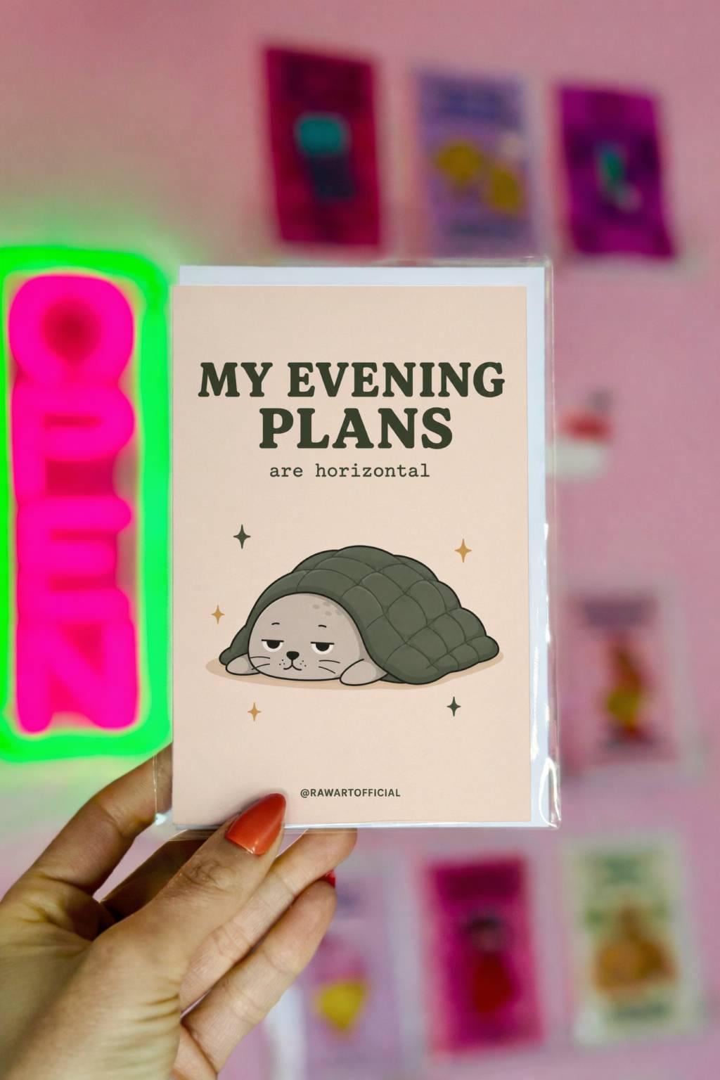 Funny greeting card with sleepy seal under blanket on cream background saying “My Evening Plans Are Horizontal”