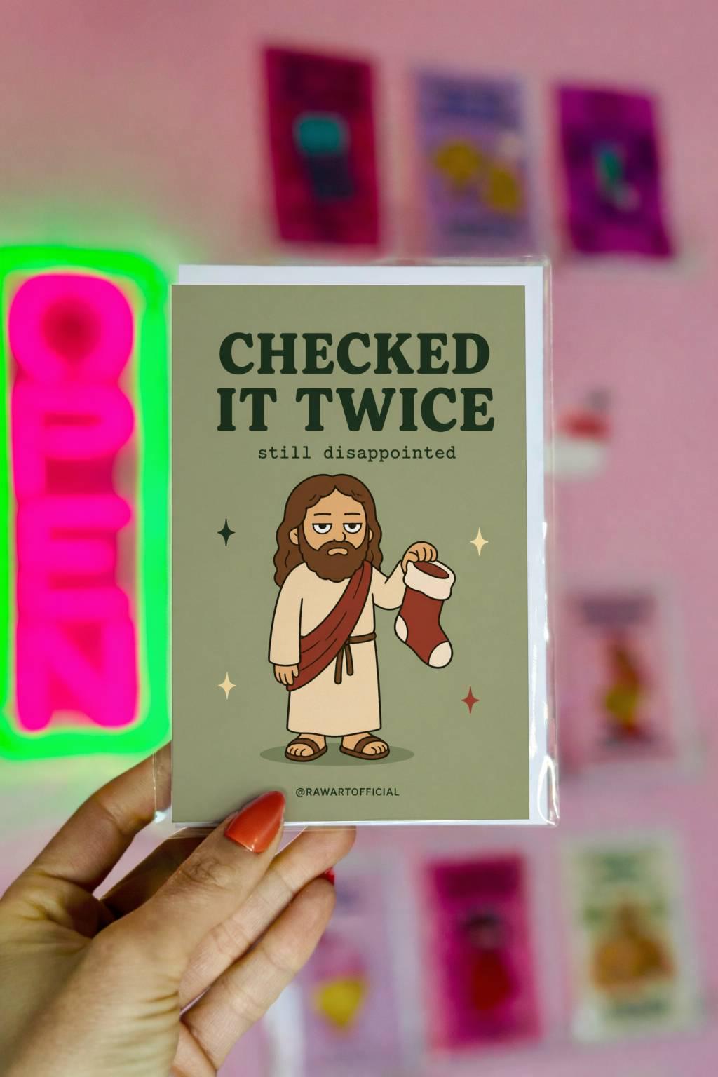 Funny Christmas greeting card with unimpressed Jesus holding a stocking on sage green background saying “Checked It Twice Still Disappointed”