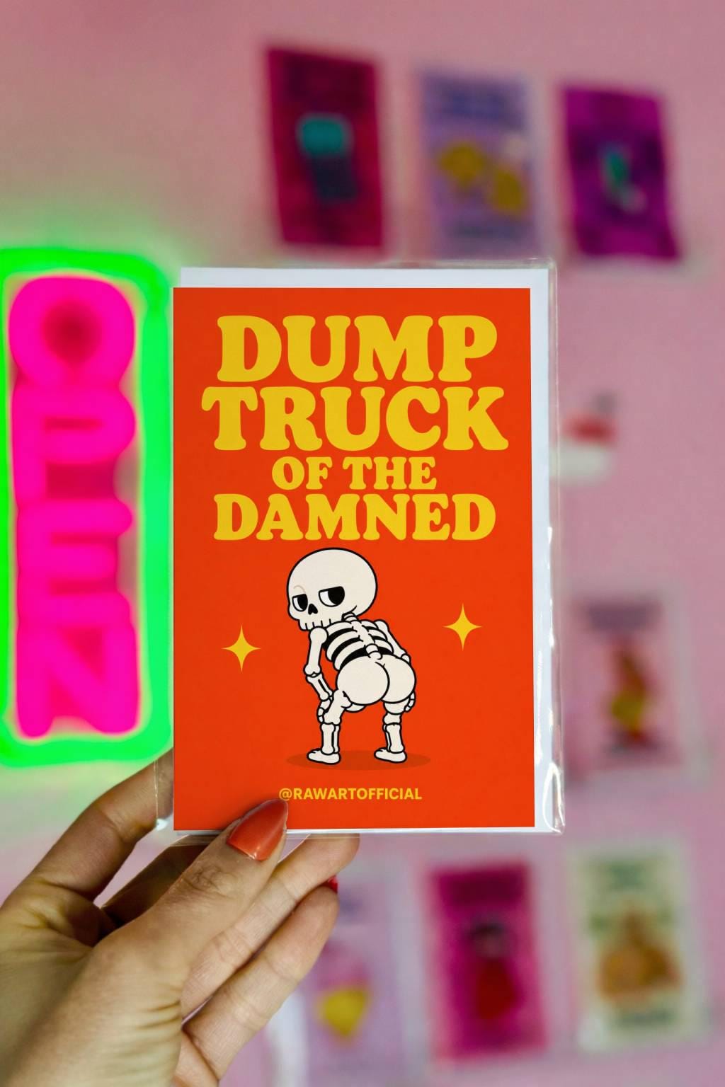 Funny Halloween greeting card with skeleton showing a dump truck booty on orange background saying “Dump Truck of the Damned”