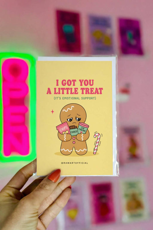 Funny Christmas card featuring a gingerbread cookie holding chips, chocolate, and ice cream beside the phrase “I Got You A Little Treat (It’s Emotional Support).”