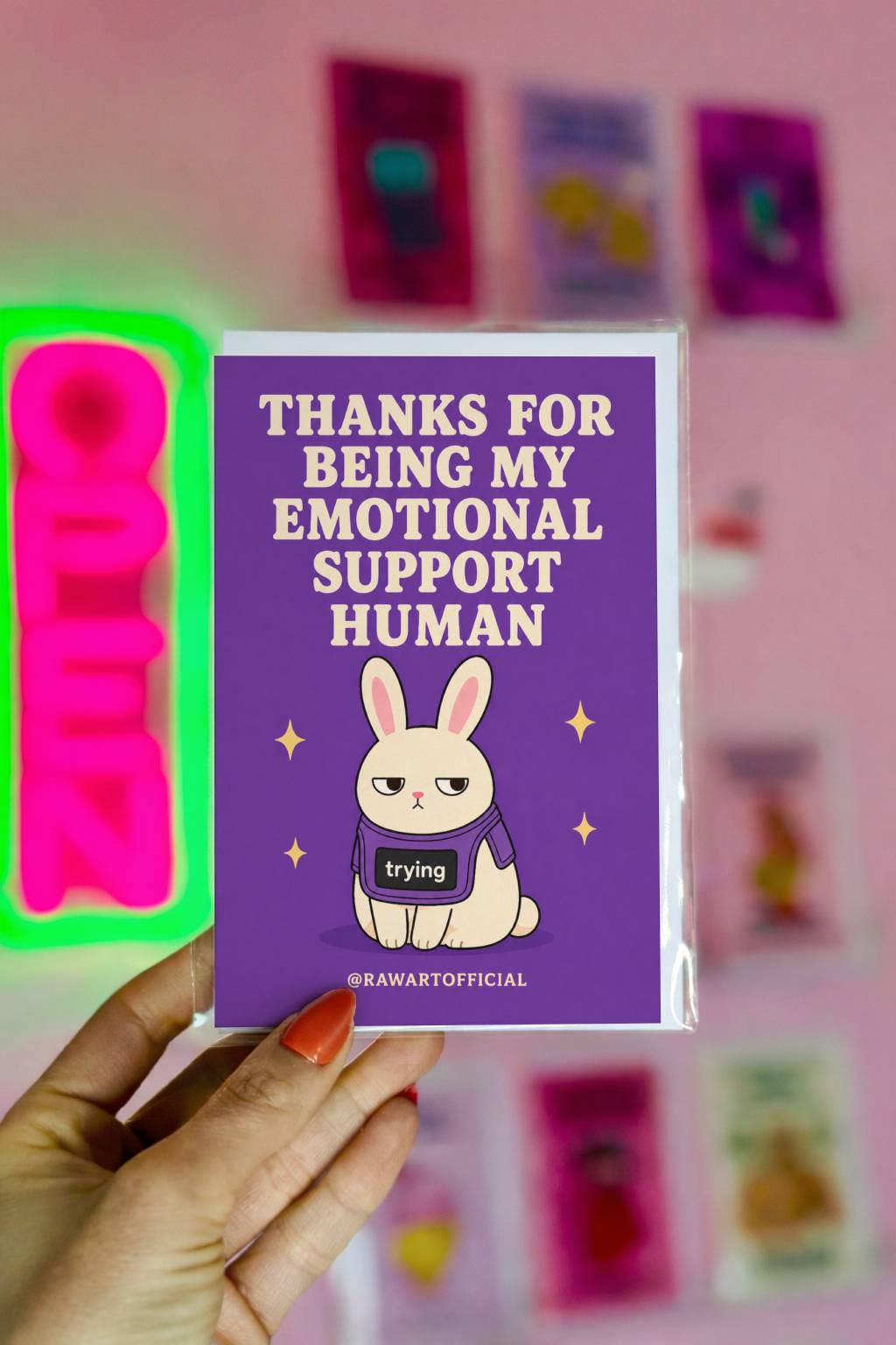 Funny appreciation card featuring a bunny in a “trying” shirt beside the phrase “Thanks For Being My Emotional Support Human.”