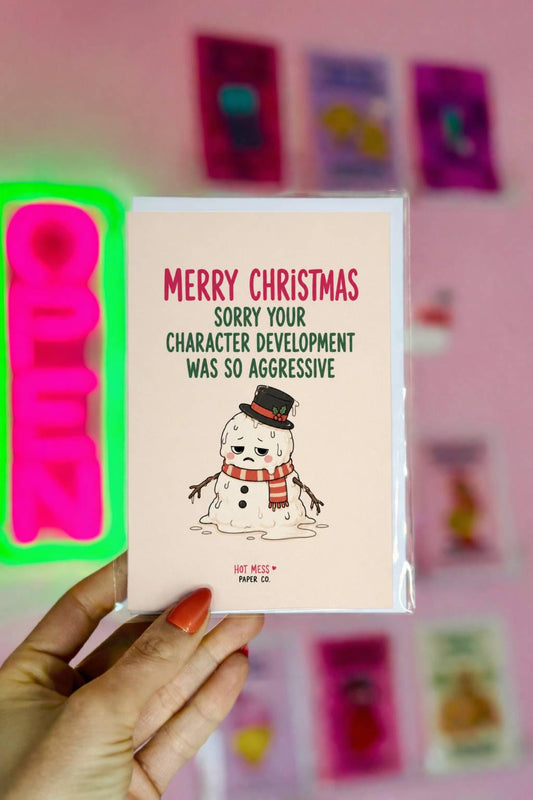 Funny Christmas card featuring a melting snowman beside the phrase “Sorry Your Character Development Was So Aggressive.”