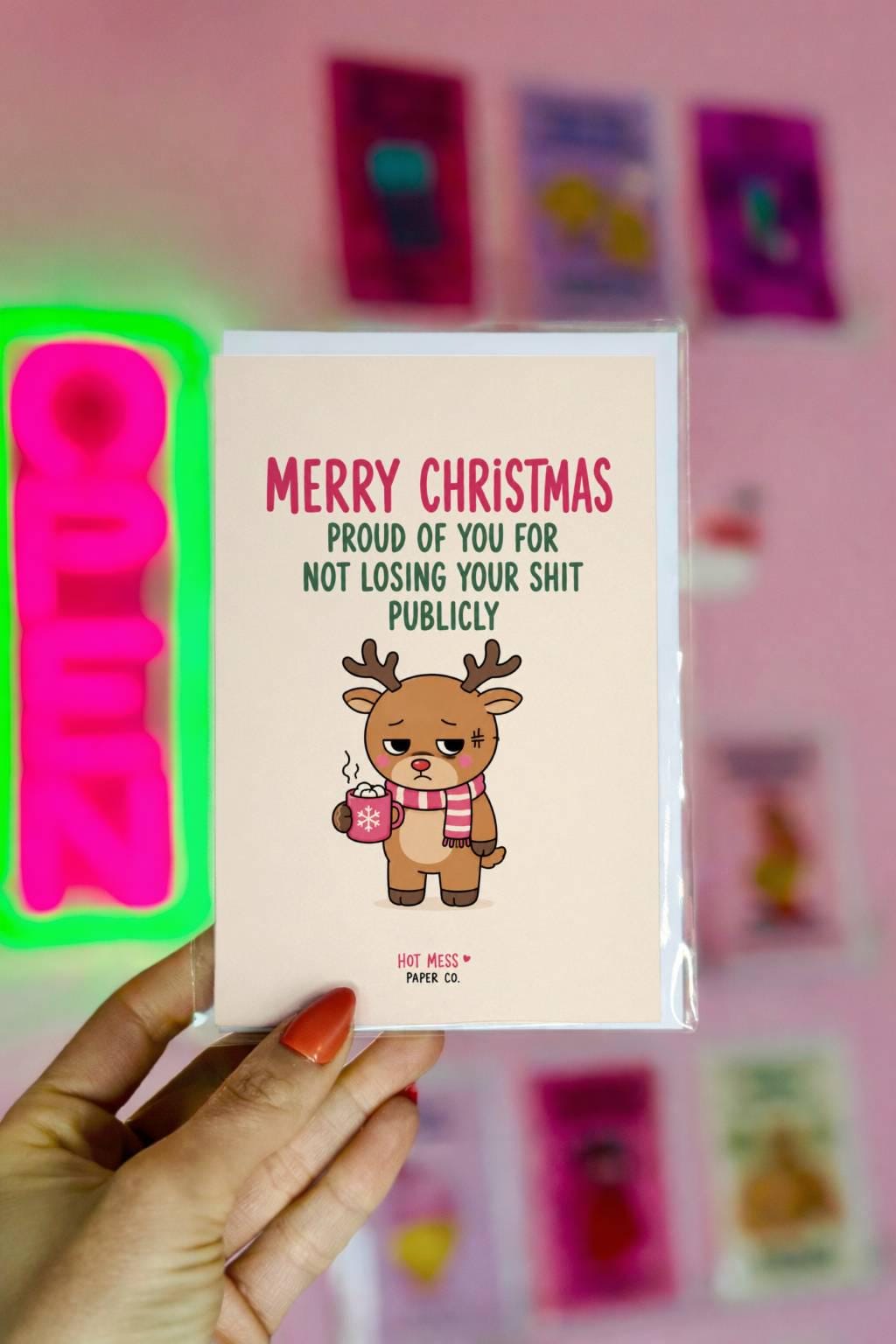 Funny Christmas card featuring a tired reindeer holding hot cocoa beside the phrase “Proud Of You For Not Losing Your Shit Publicly.”