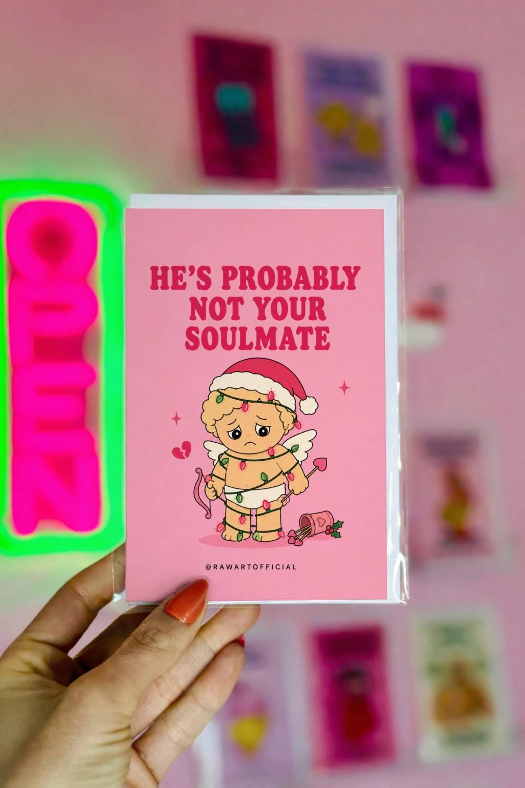 Funny Christmas card featuring a sad cupid tangled in Christmas lights beside the phrase “He’s Probably Not Your Soulmate.”