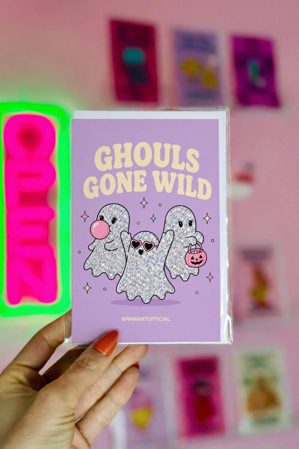 Lavender Halloween greeting card reading "Ghouls Gone Wild" featuring three glittery cute ghosts, one blowing bubblegum, one wearing heart sunglasses, and one carrying a pumpkin candy bucket.