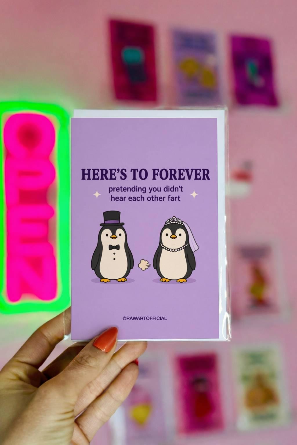 Funny wedding card featuring bride and groom penguins with the phrase “Here’s to Forever Pretending You Didn’t Hear Each Other Fart.”