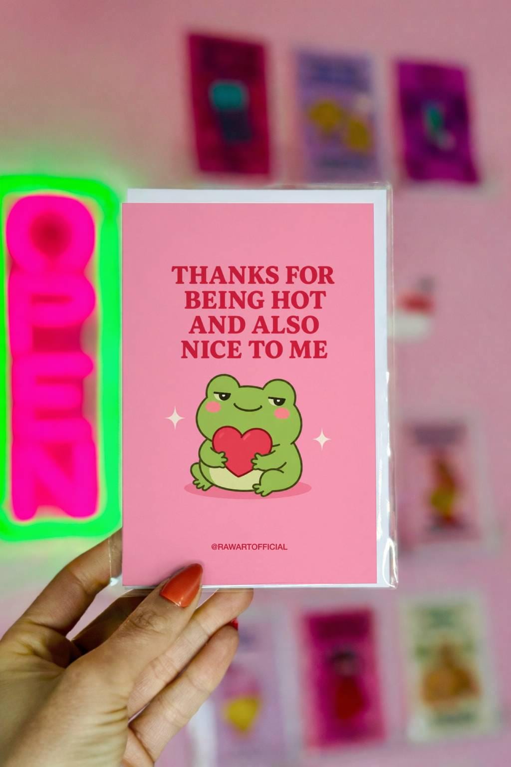 Funny love card featuring a green frog hugging a red heart beside the phrase “Thanks for Being Hot and Also Nice to Me.”