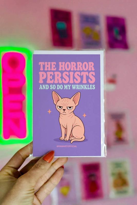 Funny birthday greeting card featuring a grumpy wrinkled Sphynx cat beneath the phrase “The Horror Persists and So Do My Wrinkles.” A funny aging card for Sphynx and hairless cat lovers.