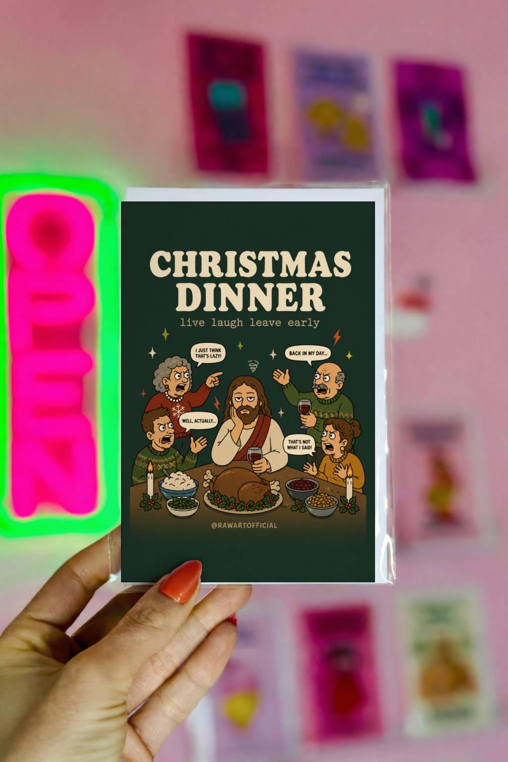 Funny Christmas card featuring Jesus sitting at a chaotic family Christmas dinner with relatives arguing around the table and the phrase “Christmas Dinner – Live Laugh Leave Early.”