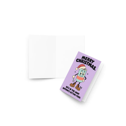 Funny Christmas greeting card featuring a cartoon energy drink can wearing a red Santa hat, brown work boots, and white gloves while holding a wrench. Pastel lavender background with bold black retro lettering reading “Merry Christmas. He's in the Shop. Nothing's Getting Fixed.” Humorous holiday card for mechanics, oilfield workers, tradesmen, and garage enthusiasts.