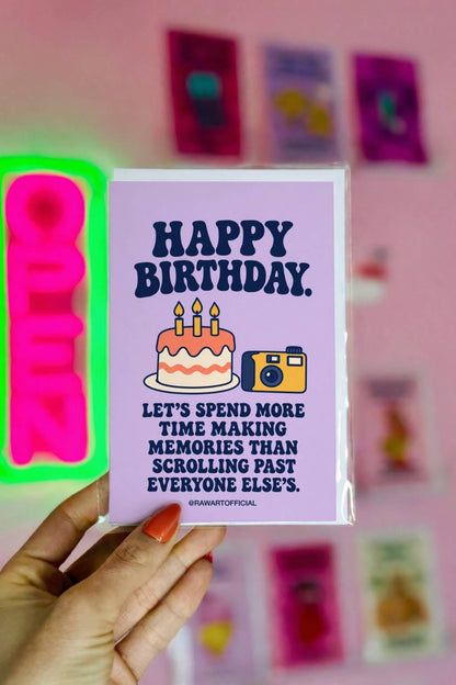 Thoughtful birthday greeting card featuring a frosted birthday cake with three lit candles beside a yellow and navy retro camera on a pastel lavender background. Bold navy lettering reads “Happy Birthday. Let's Spend More Time Making Memories Than Scrolling Past Everyone Else's.” Birthday card celebrating less screen time, friendship, and making real-life memories by Hot Mess Paper Co.
