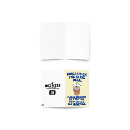 Funny influencer congratulations greeting card featuring a takeaway iced coffee cup with a blue straw, ice cubes, and pink bow on a pale yellow background. Bold blue retro lettering reads “Congrats on the Brand Deal. Please Remember Me When Your Iced Coffee Is Tax-Deductible.” Humorous celebration card for influencers, content creators, and social media brand collaborations by Hot Mess Paper Co.
 Copy alt text