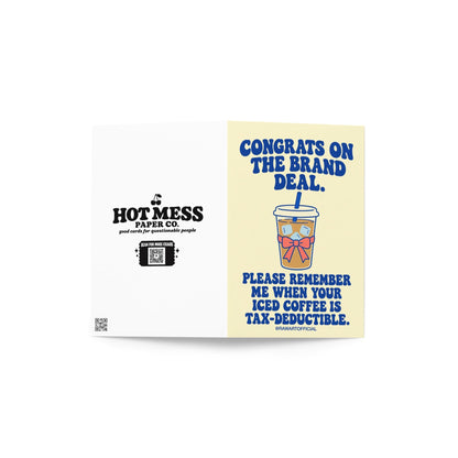 Funny influencer congratulations greeting card featuring a takeaway iced coffee cup with a blue straw, ice cubes, and pink bow on a pale yellow background. Bold blue retro lettering reads “Congrats on the Brand Deal. Please Remember Me When Your Iced Coffee Is Tax-Deductible.” Humorous celebration card for influencers, content creators, and social media brand collaborations by Hot Mess Paper Co.
 Copy alt text