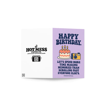 Thoughtful birthday greeting card featuring a frosted birthday cake with three lit candles beside a yellow and navy retro camera on a pastel lavender background. Bold navy lettering reads “Happy Birthday. Let's Spend More Time Making Memories Than Scrolling Past Everyone Else's.” Birthday card celebrating less screen time, friendship, and making real-life memories by Hot Mess Paper Co.