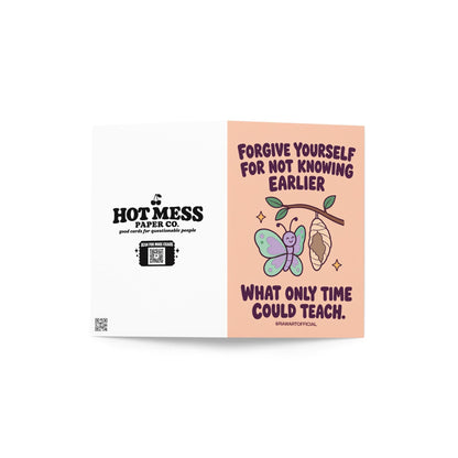 Self-forgiveness encouragement greeting card featuring a smiling pastel mint and lavender butterfly beside a hanging chrysalis on a leafy branch, with small golden sparkles. Soft peach background with bold dark plum retro lettering reading “Forgive Yourself for Not Knowing Earlier What Only Time Could Teach.” Inspirational personal growth and self-compassion card by Hot Mess Paper Co.