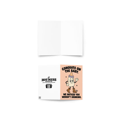 Funny pregnancy congratulations greeting card featuring a smiling cartoon baby bottle with a lavender collar, white gloves, and brown cowboy boots, waving on a peach background. Bold black retro lettering reads “Congrats on the Baby. We Noticed You Weren't Drinking.” Cheeky pregnancy announcement and expecting-parent congratulations card by Hot Mess Paper Co.