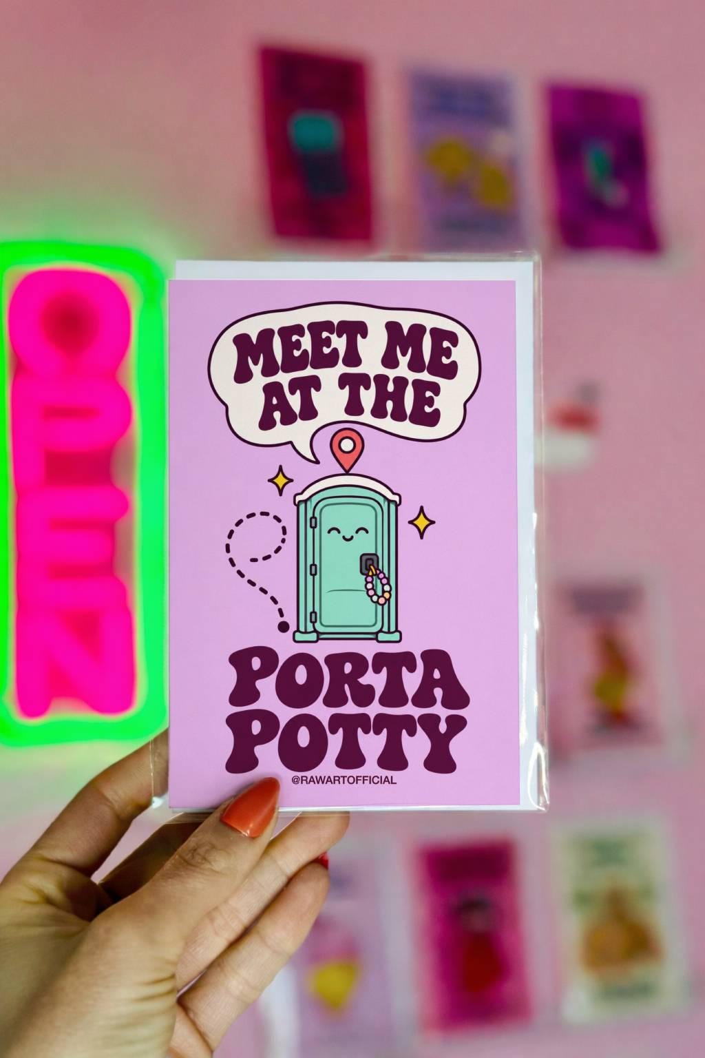 Funny rave festival card featuring a smiling mint-green porta potty decorated with colourful kandi bracelets, a location pin, and yellow sparkles against a pastel lavender background. Bold retro purple lettering reads “Meet Me at the Porta Potty.” Humorous EDM friendship greeting card for music festival besties and ravers.