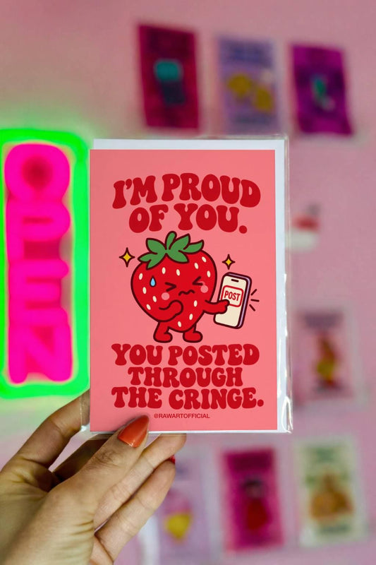Coral-pink content creator encouragement greeting card with bold red retro lettering reading “I'm Proud of You. You Posted Through the Cringe.” Features a cute red cartoon strawberry with a nervous expression and a sweat drop, holding a smartphone displaying a POST button, surrounded by small yellow sparkles. Funny supportive card for influencers, TikTok creators, Instagram content creators, and anyone overcoming the fear of posting online.