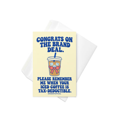 Funny influencer congratulations greeting card featuring a takeaway iced coffee cup with a blue straw, ice cubes, and pink bow on a pale yellow background. Bold blue retro lettering reads “Congrats on the Brand Deal. Please Remember Me When Your Iced Coffee Is Tax-Deductible.” Humorous celebration card for influencers, content creators, and social media brand collaborations by Hot Mess Paper Co.
 Copy alt text