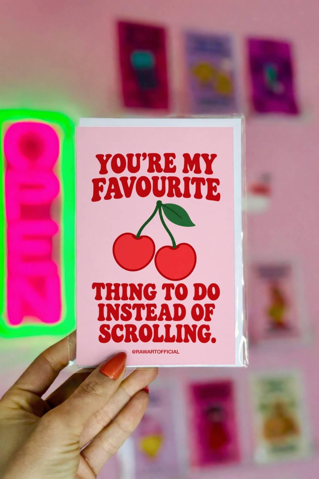 Funny romantic greeting card featuring two bright red cherries connected by green stems with a single leaf on a soft pink background. Bold red retro lettering reads “You're My Favourite Thing to Do Instead of Scrolling.” Sweet love card celebrating less screen time, more quality time, and real-life connection by Hot Mess Paper Co.