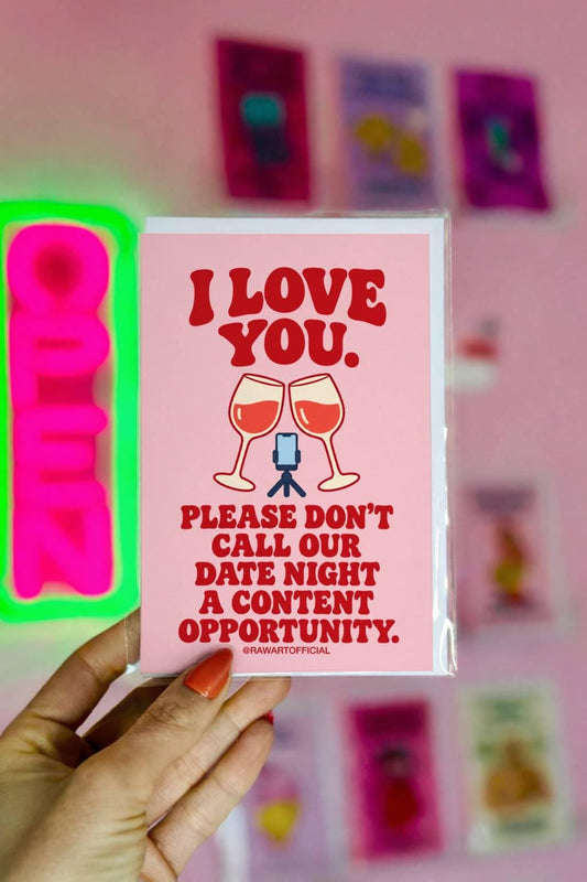Funny influencer love greeting card featuring two clinking wine glasses filled with red wine beside a miniature phone on a tripod. Soft pink background with bold red retro lettering reading “I Love You. Please Don't Call Our Date Night a Content Opportunity.” Humorous romantic card for content creators, influencer couples, and social media lovers by Hot Mess Paper Co.
 Copy alt text