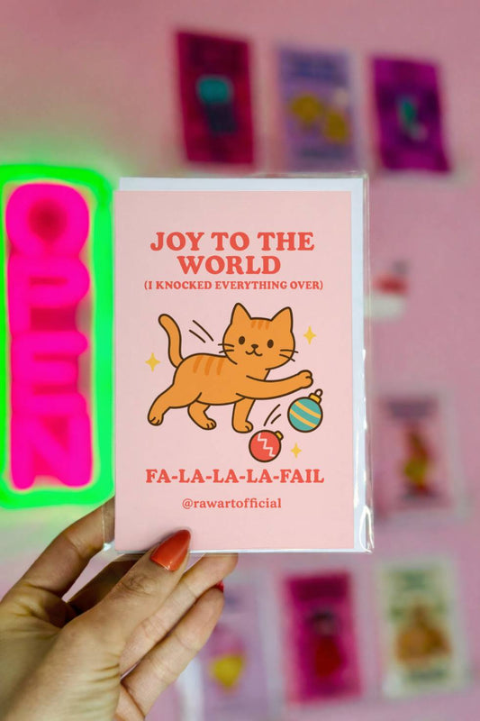 Funny Christmas card showing orange cat knocking ornaments over with text “Joy to the World I Knocked Everything Over.”