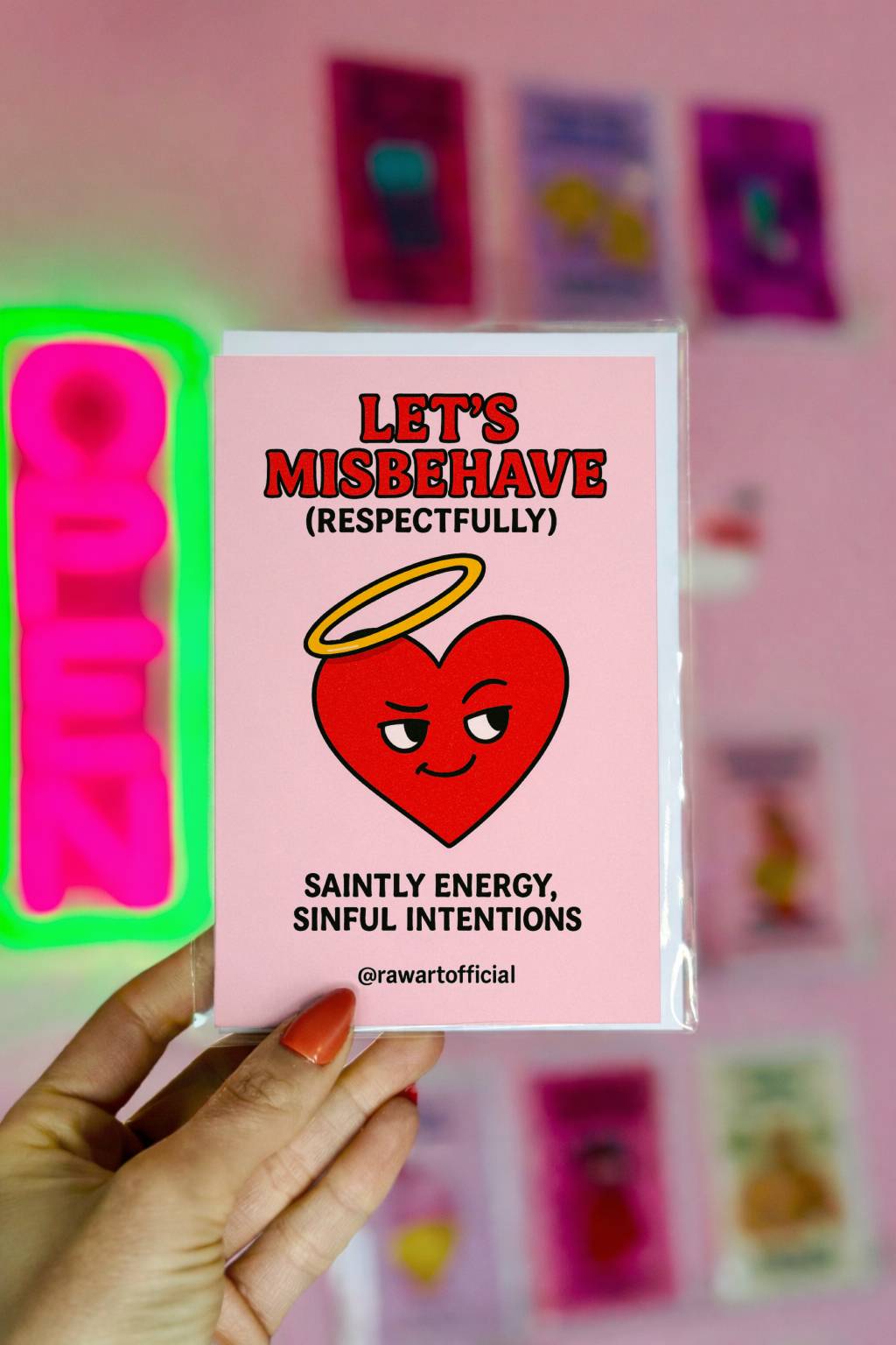 Pink greeting card reading Let’s Misbehave (Respectfully) with smirking heart illustration and @rawartofficial signature.