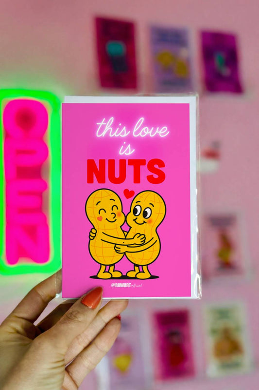 Funny greeting card reading “This Love Is Nuts” with two cartoon peanuts hugging on a bright pink background.