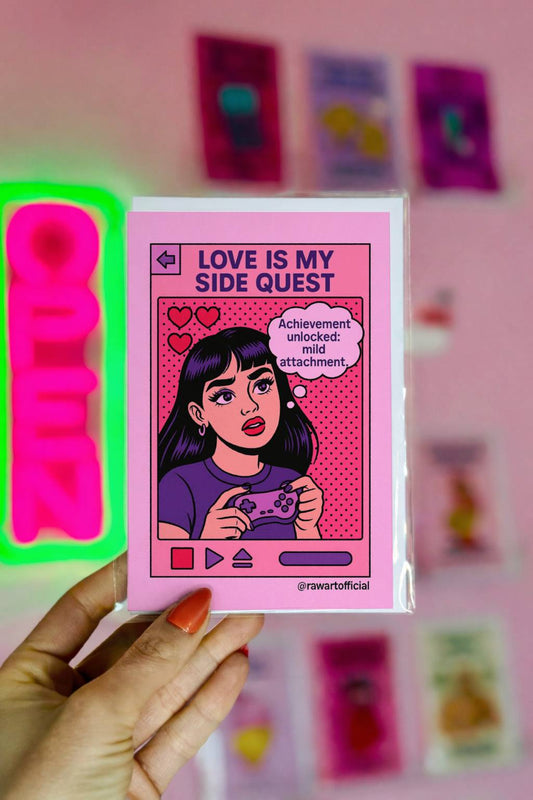 Retro pop art greeting card featuring a gamer girl holding a controller with the text “Love Is My Side Quest” and “Achievement unlocked: mild attachment.”