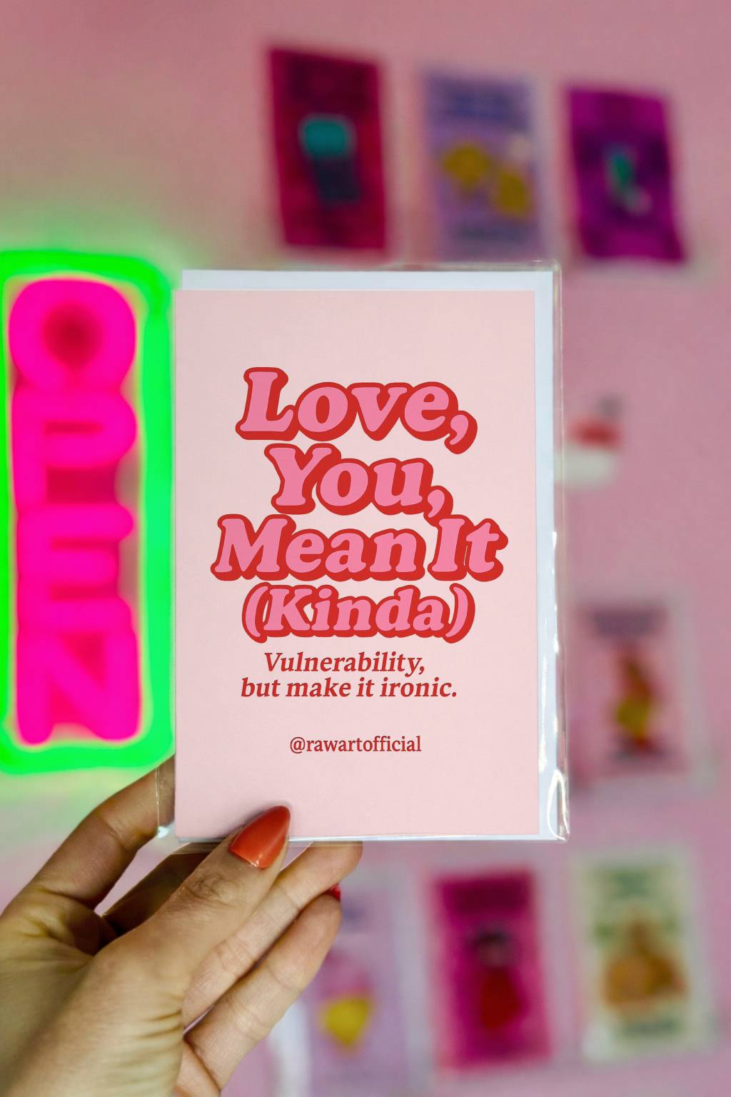 Pink greeting card with bold red retro text reading Love You Mean It (Kinda) Vulnerability but make it ironic and @rawartofficial signature.