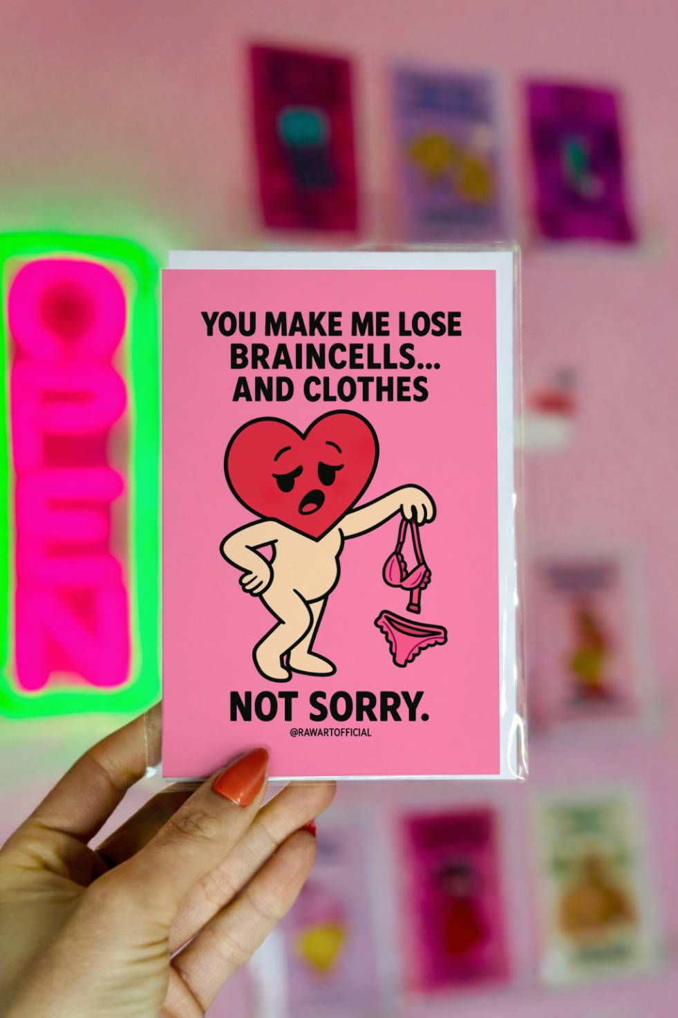 Funny greeting card reading “You Make Me Lose Braincells and Clothes” with a cartoon heart holding bra and underwear on a pink background.