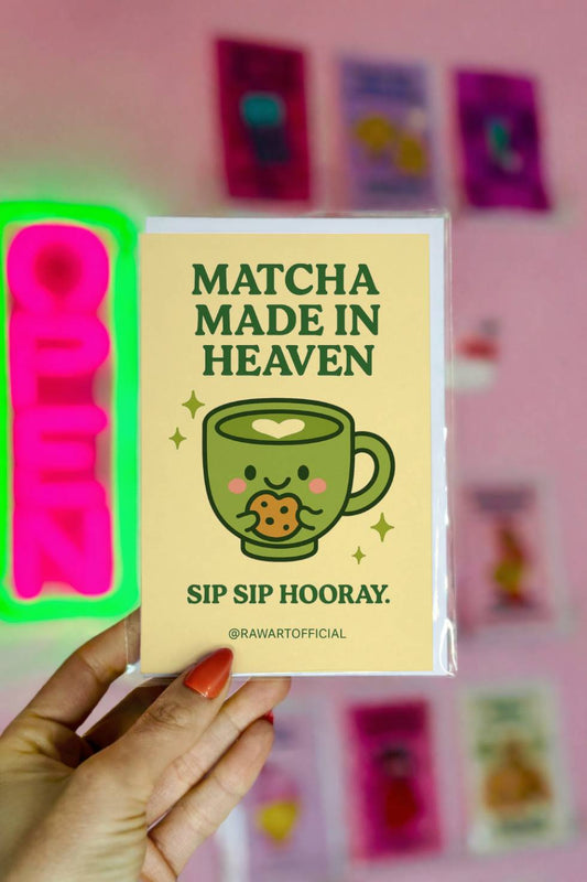 Greeting card with a smiling matcha cup holding a cookie and text reading “Matcha Made in Heaven.”