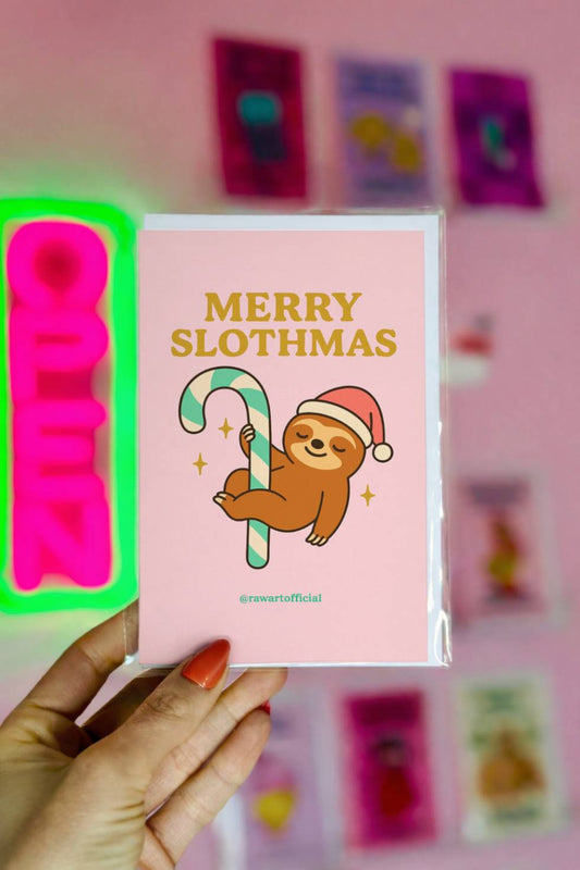 Christmas greeting card featuring a sloth wearing a Santa hat hanging from a candy cane with the text “Merry Slothmas.”