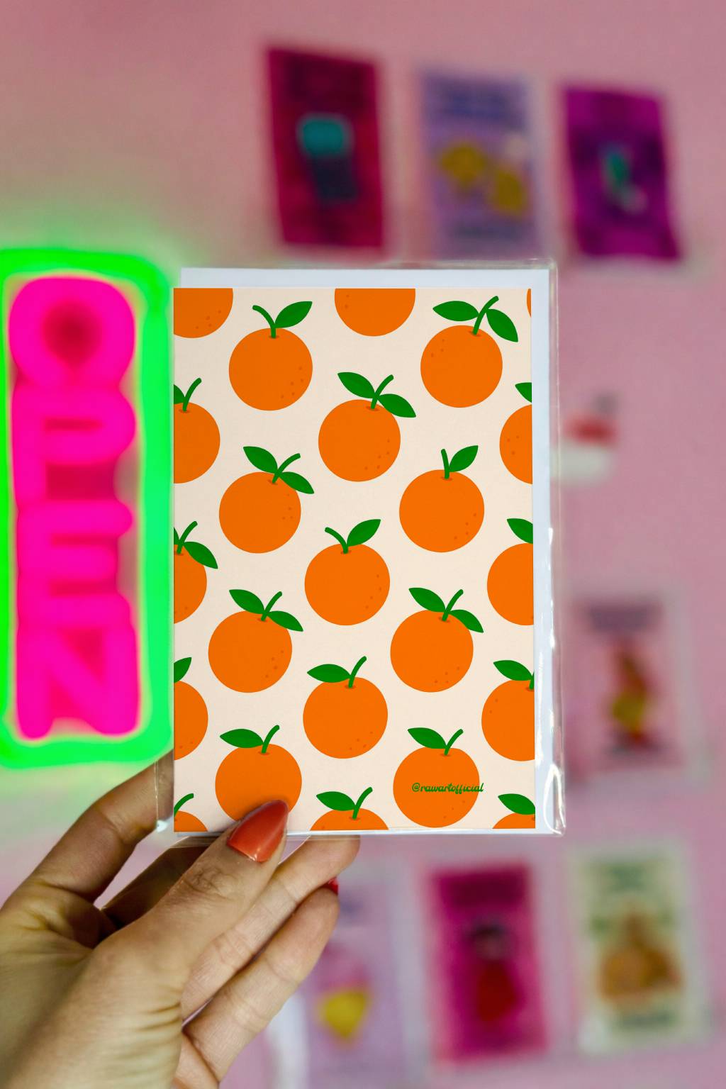 Greeting card featuring a repeating pattern of illustrated oranges with green leaves on a warm neutral background.