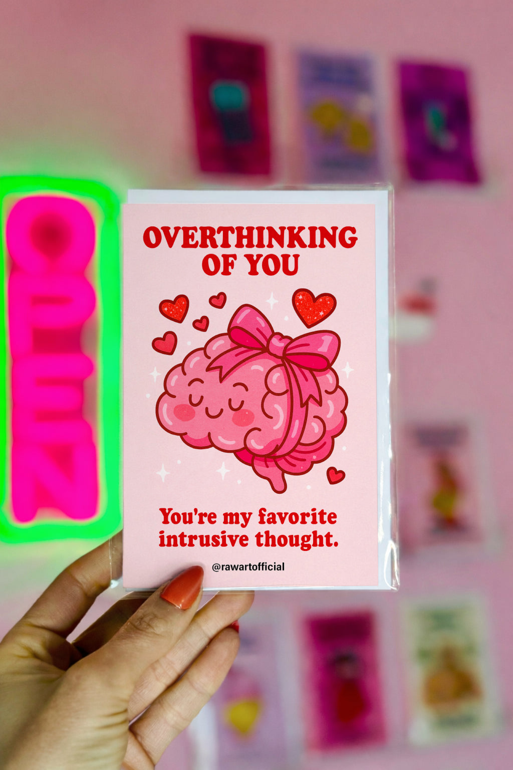 Cute pink Love card with a cartoon brain tied in a bow surrounded by hearts, captioned “Overthinking of You – You’re my favorite intrusive thought.”