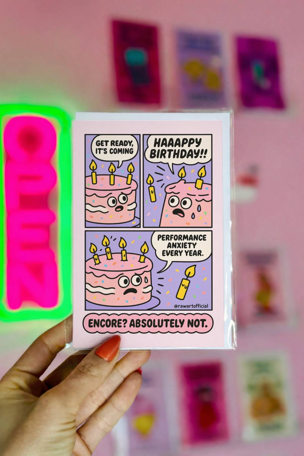 Comic-style pink birthday card - cake with candles panicking during “Happy Birthday” song, text reads “Encore? Absolutely Not.”