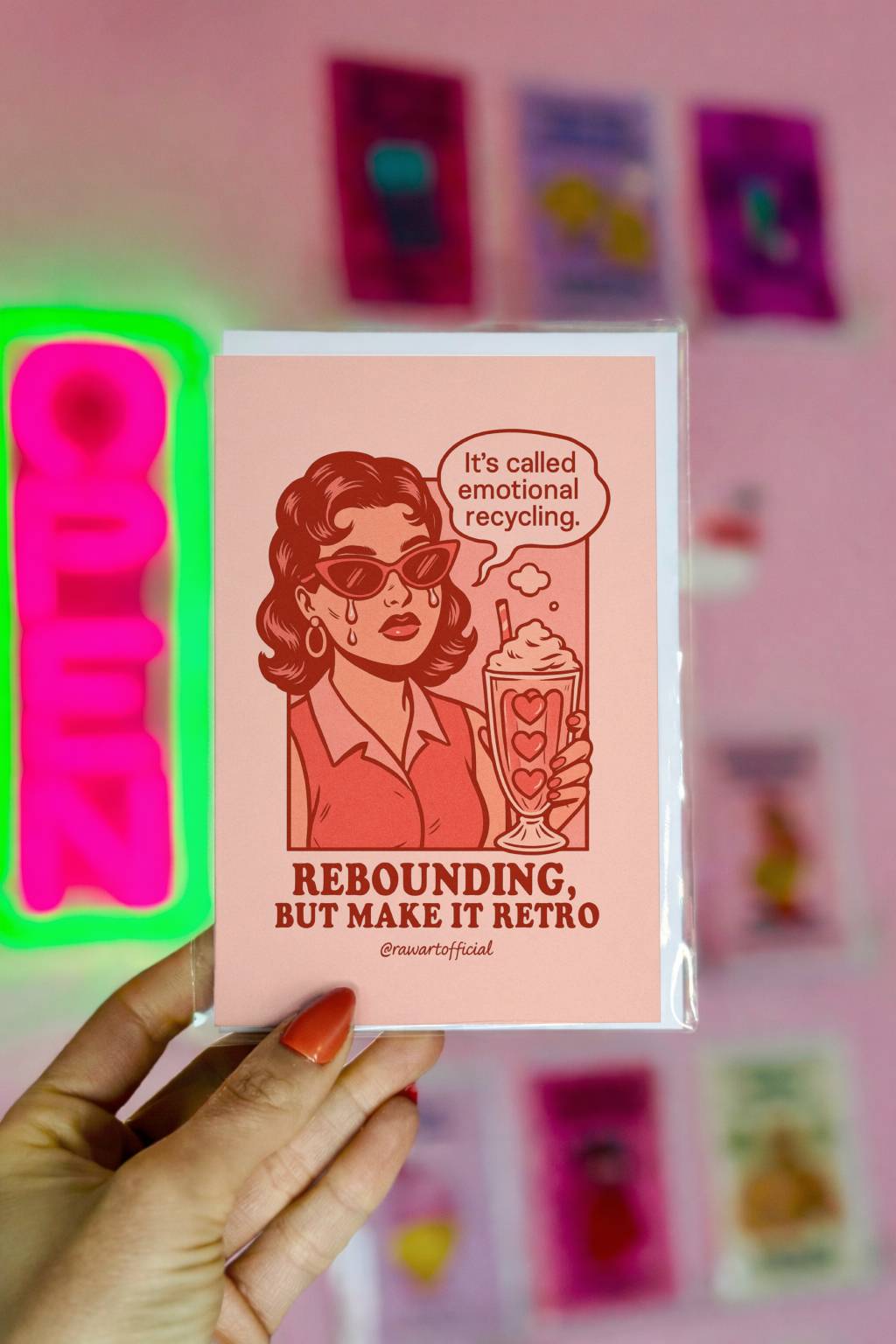 Retro pop art greeting card featuring a woman in sunglasses holding a heart milkshake with the text “Rebounding, But Make It Retro” and “It’s called emotional recycling.”