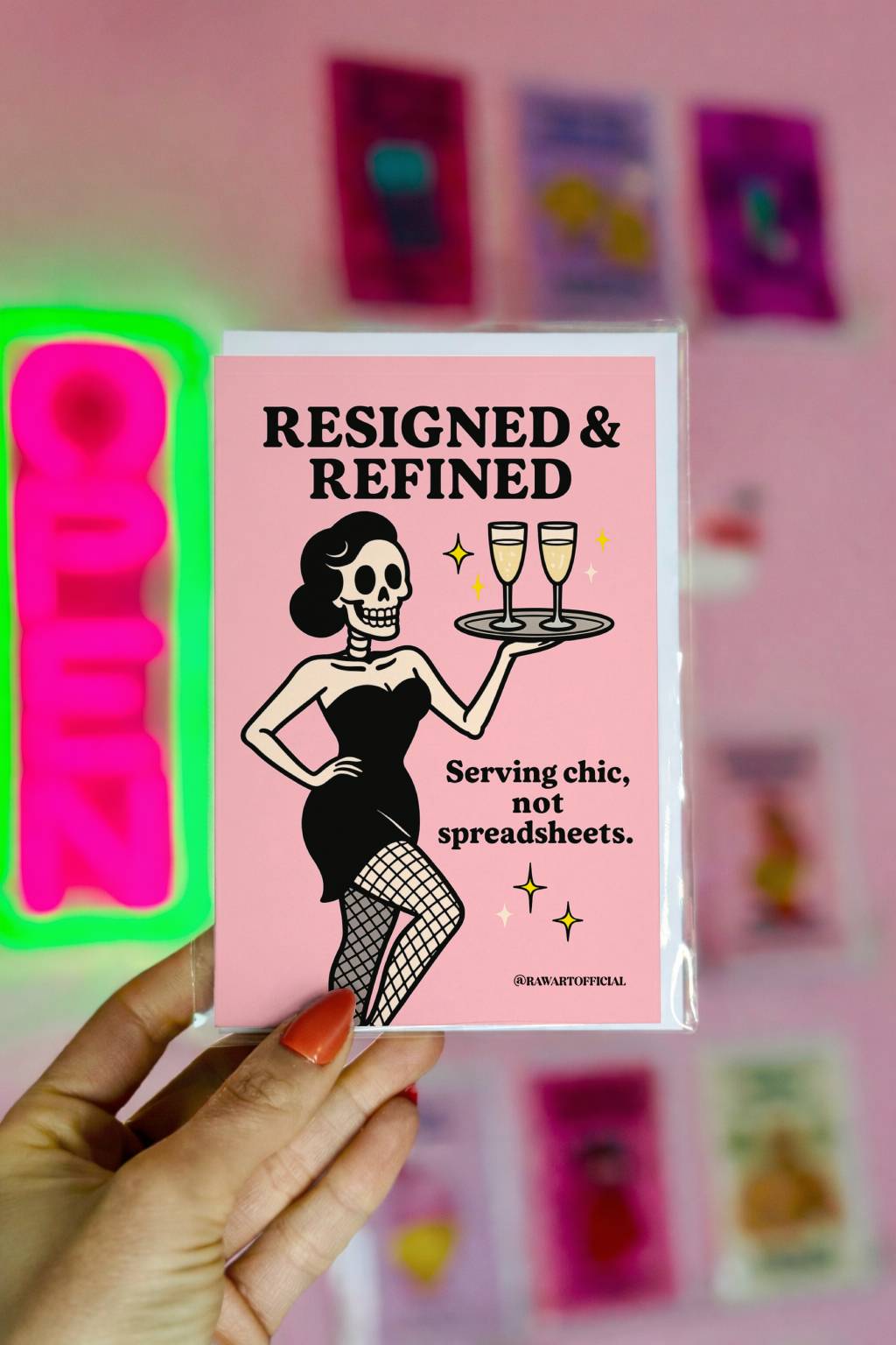 Pink congratulations card featuring a glamorous skeleton holding champagne with the phrase “Resigned & Refined – Serving chic, not spreadsheets.”