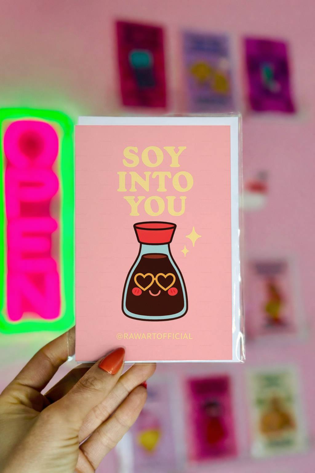 Pink greeting card with yellow text reading Soy Into You and smiling soy sauce bottle with heart eyes, signed @rawartofficial.