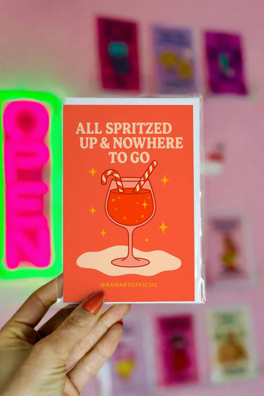 Funny Christmas greeting card featuring a festive cocktail with candy cane straws and text reading “All Spritzed Up and Nowhere to Go.”
