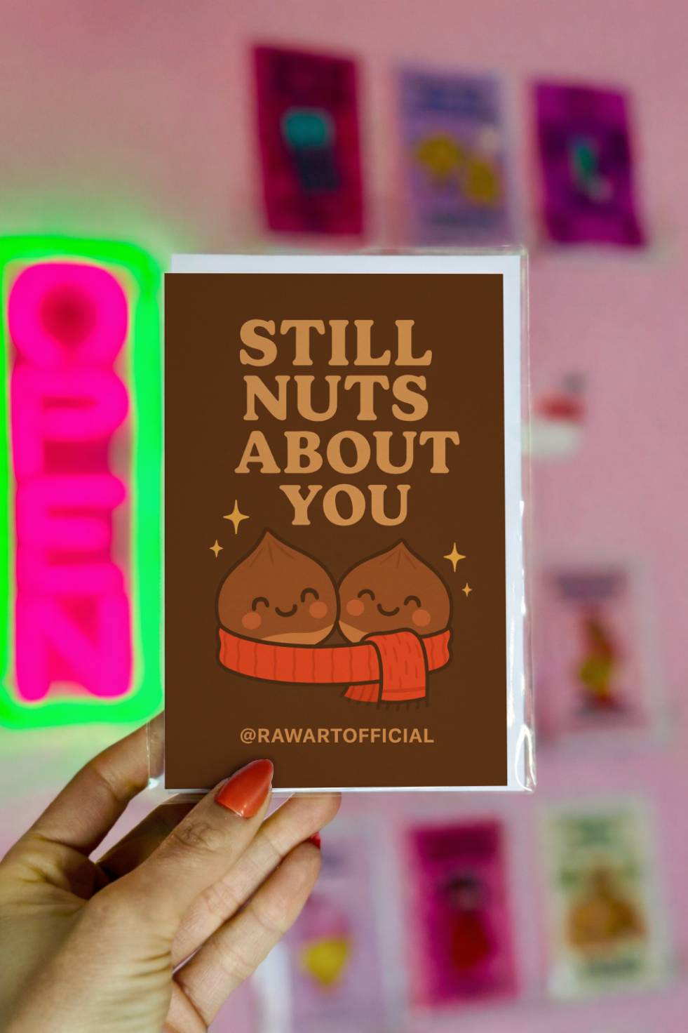 Funny greeting card reading “Still Nuts About You” with two cute chestnuts wearing a scarf on a brown background.