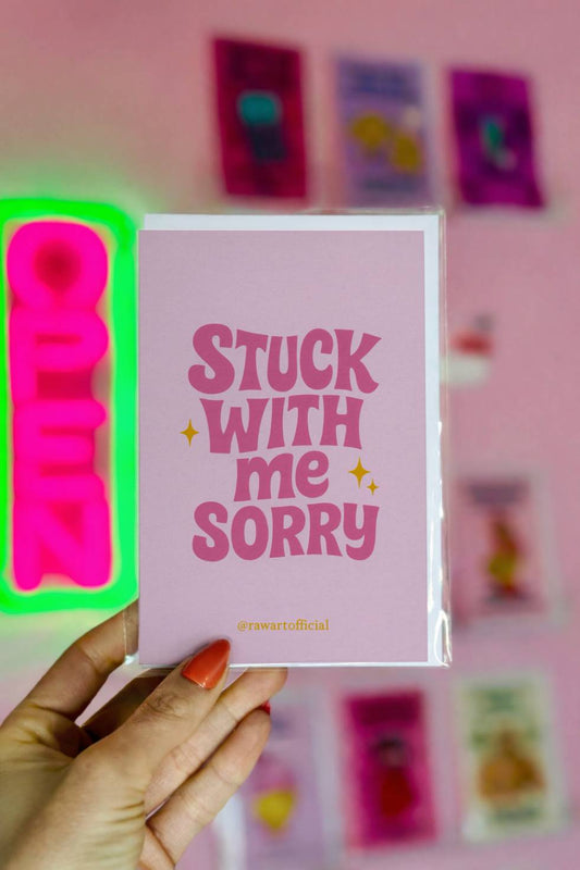 Funny greeting card with retro pink lettering reading “Stuck With Me Sorry” on a light pastel background.
