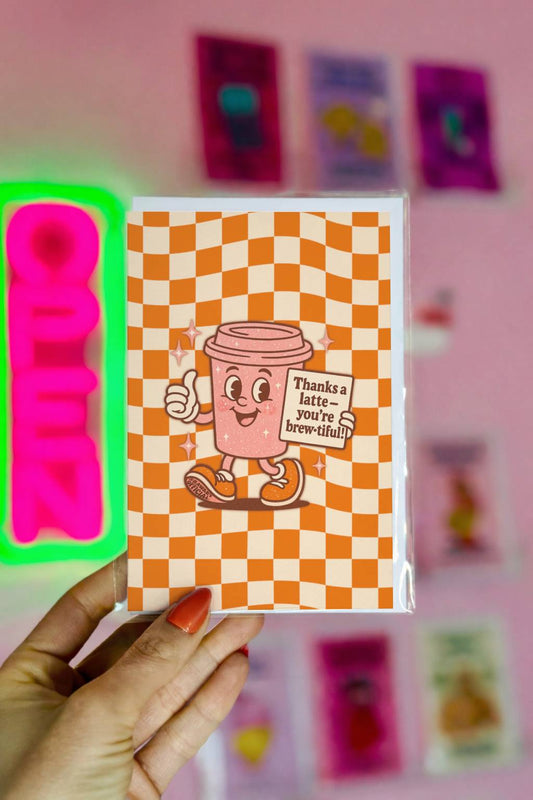Retro coffee-themed thank you card featuring a smiling latte cup holding a sign that says “Thanks a latte – you’re brew-tiful” on an orange checkerboard background.