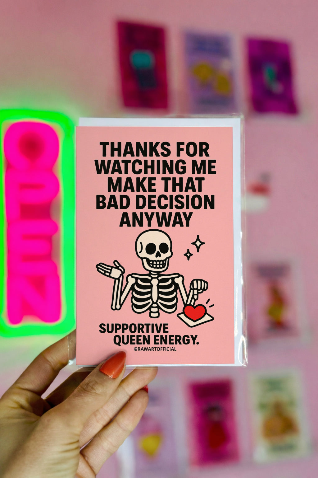 Pink card with cute cartoon skeleton shrugging while holding a heart tray and text saying “Thanks for watching me make that bad decision anyway.”